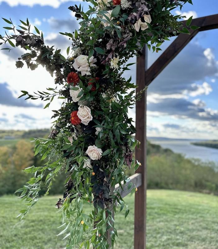 Outdoor wedding ceremony arch with roses and greenery